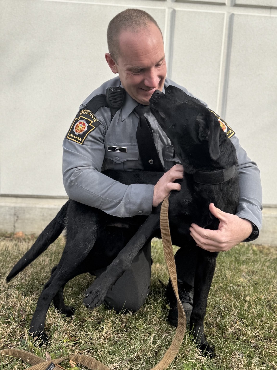 Pennsylvania State Trooper kneeling with Gunner during therapy dog support visit